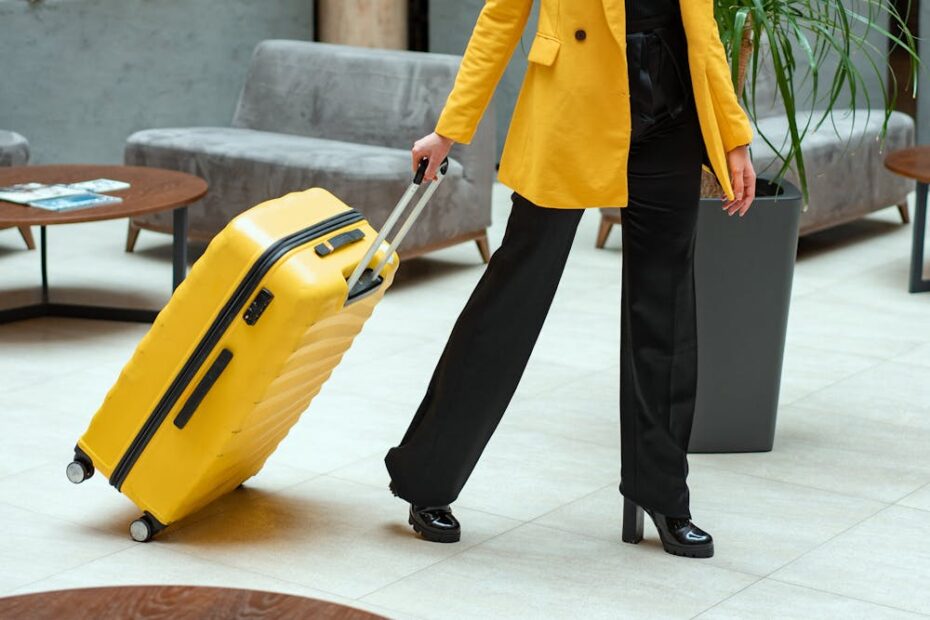 Woman in a yellow coat rolls her yellow suitcase